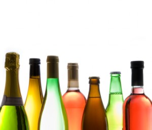 Different styles of wine and beer in their bottles, backlit, copy space